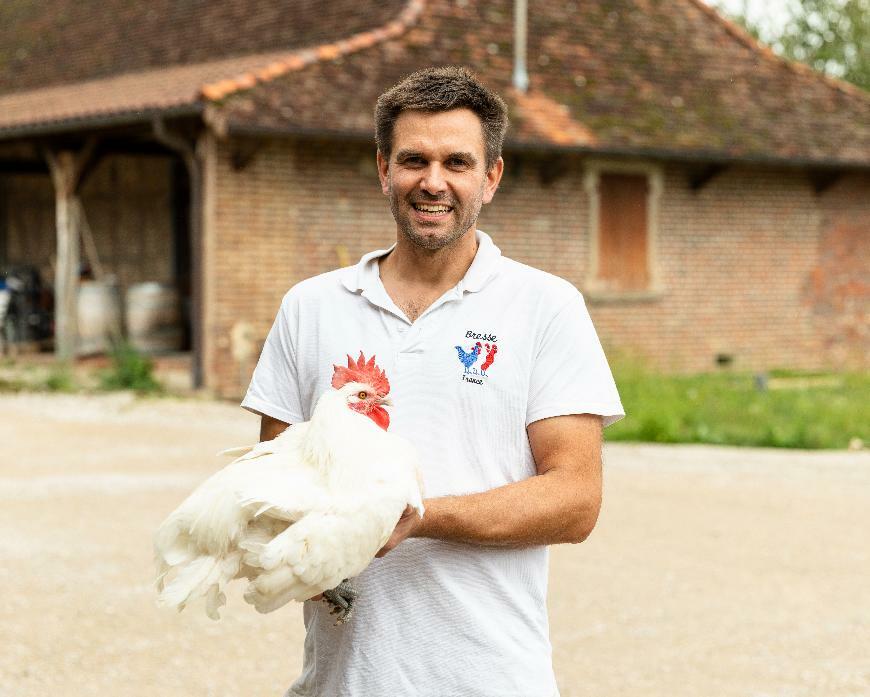 éleveur souriant avec une poule, accompagne par Cerfrance